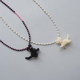 Two beaded necklaces with cat pendants on a gray background