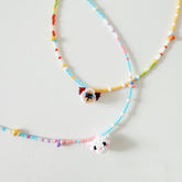 Colorful beaded necklaces with cat-shaped charms on a light gray background
