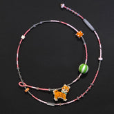 Beaded necklace with a small Shiba Inu dog charm on a black background