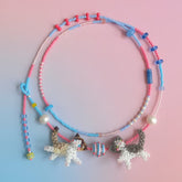 Beaded necklace with cat charms on a gradient pink and blue background