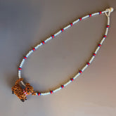 Handmade necklace with a beaded poodle dog on a plain background - verhalojewelry