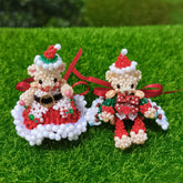 Two beaded Santa Claus figures on a grassy background