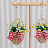 Handmade earrings with floral designs and red bows on a stand.