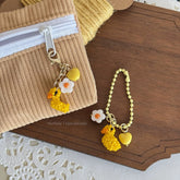 Yellow keychain with duck and flower charms on a wooden surface