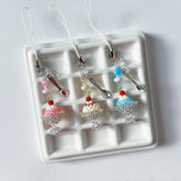 Three decorative charms resembling pudding cake on a white tray.