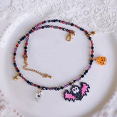 Colorful beaded necklace with pixelated ghost and bat charm on a white lace background