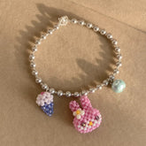 Pearl bracelet with a pink bunny charm on a beige background