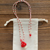 Beaded mushroom necklace with red and white beads on a wooden surface