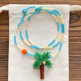 Beaded necklace with a palm tree design on a white fabric background