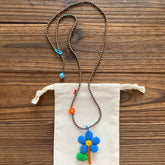 Beaded necklace with a floral pendant on a wooden surface