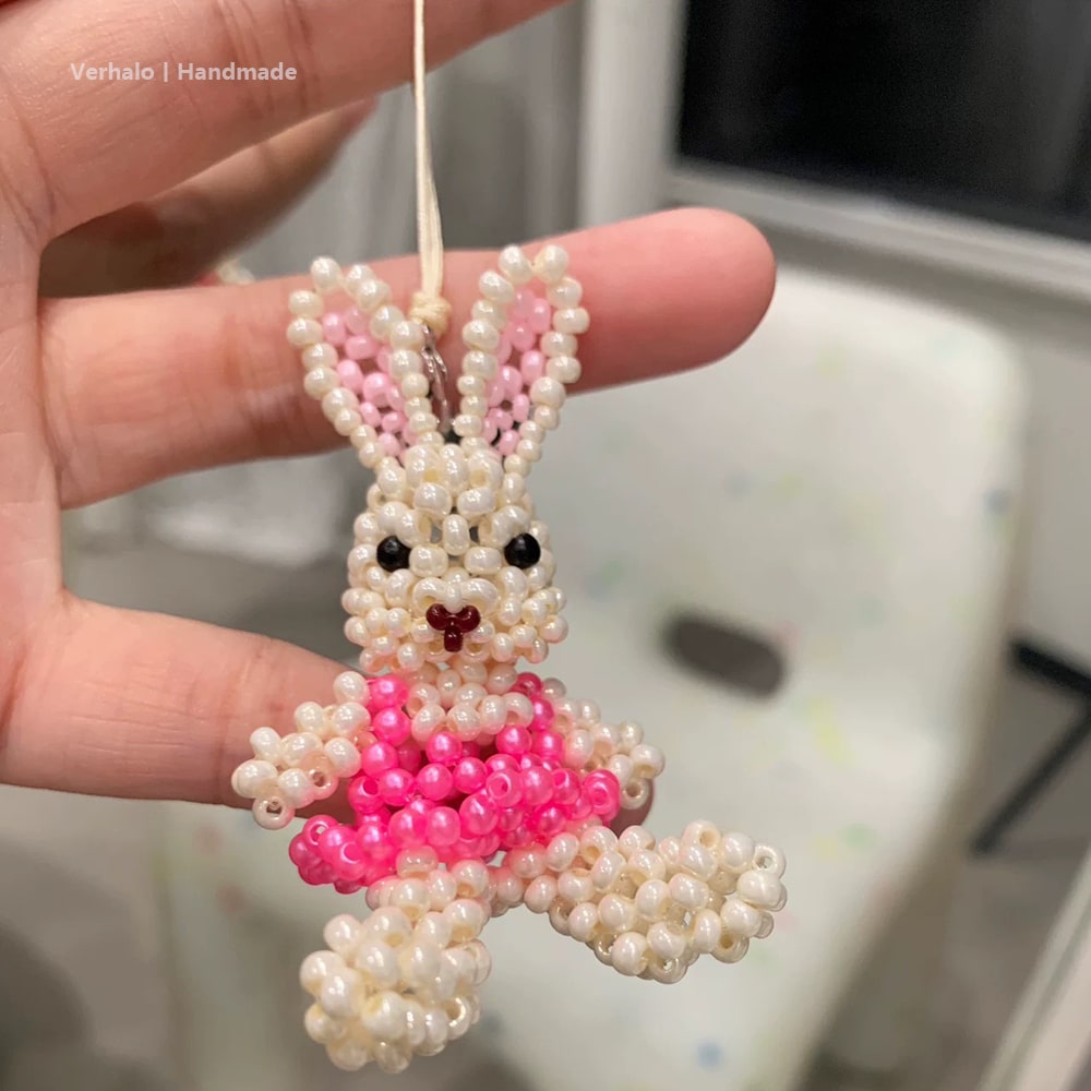 Handmade beaded bunny ornament with pink dress held by a hand.