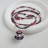 Beaded necklace with a blackberry cake pendant on a white surface