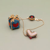 Beaded gift box bag chatm set with heart-shaped pendants on a light green background