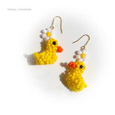 Handmade yellow duck earrings with orange flowers on a white background