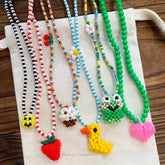 Colorful beaded necklaces with various charms on a wooden surface