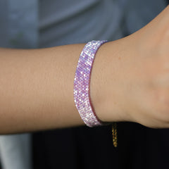 Close-up of a wrist wearing a pink glittery bracelet with a blurred background