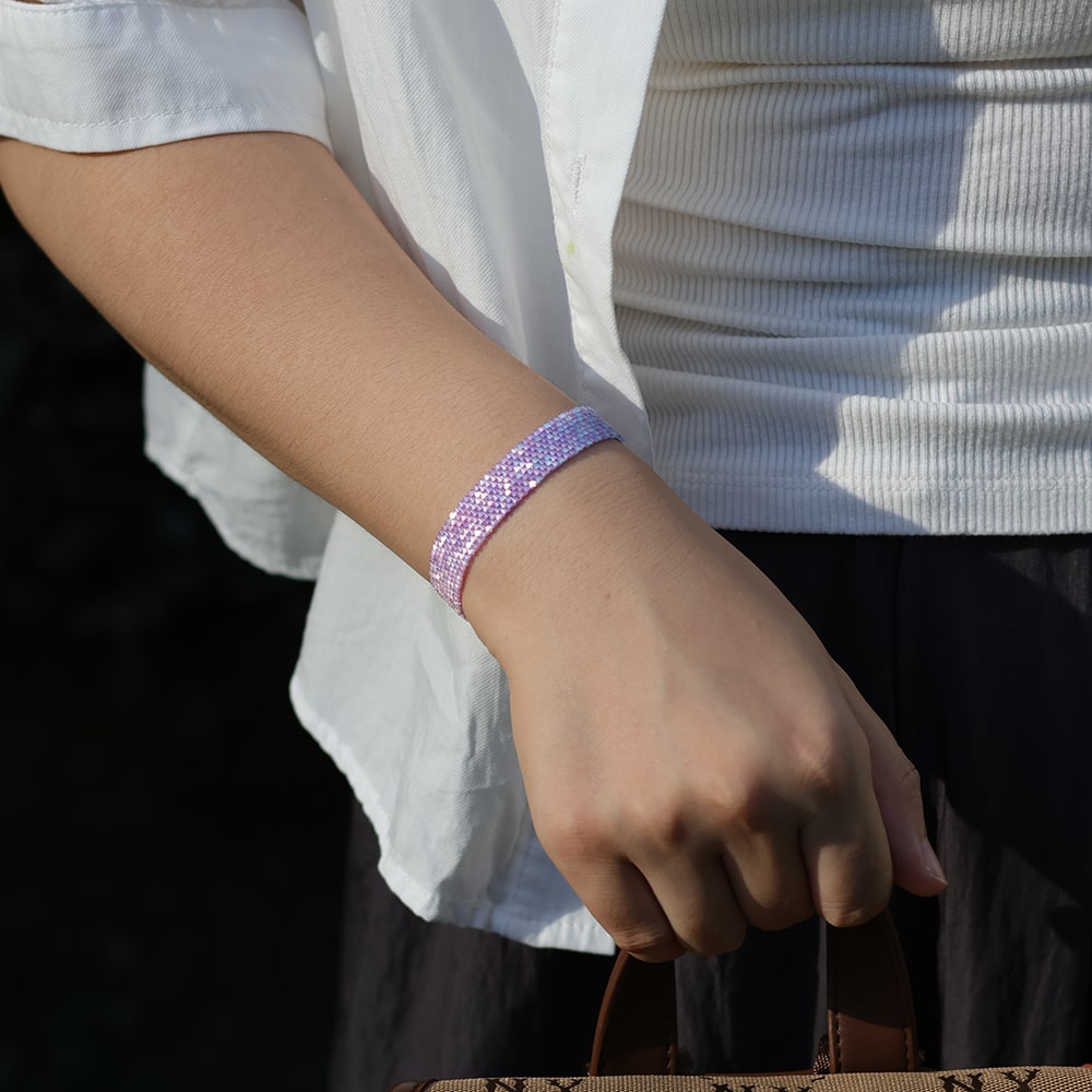 Person wearing a sparkly purple bracelet on a blurred background