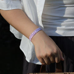 Person wearing a sparkly purple bracelet on a blurred background