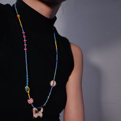 Person wearing a colorful beaded Siamese cat necklace against a plain background