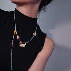 Colorful beaded necklace with a Siamese cat pendant worn by a person against a neutral background