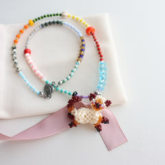 Colorful beaded cat necklace with a decorative bow on a white background