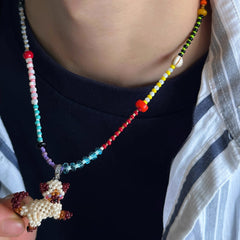 Colorful beaded necklace with a cat-shaped charm held by a person wearing a black shirt.