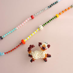Beaded cat charm on a pink background