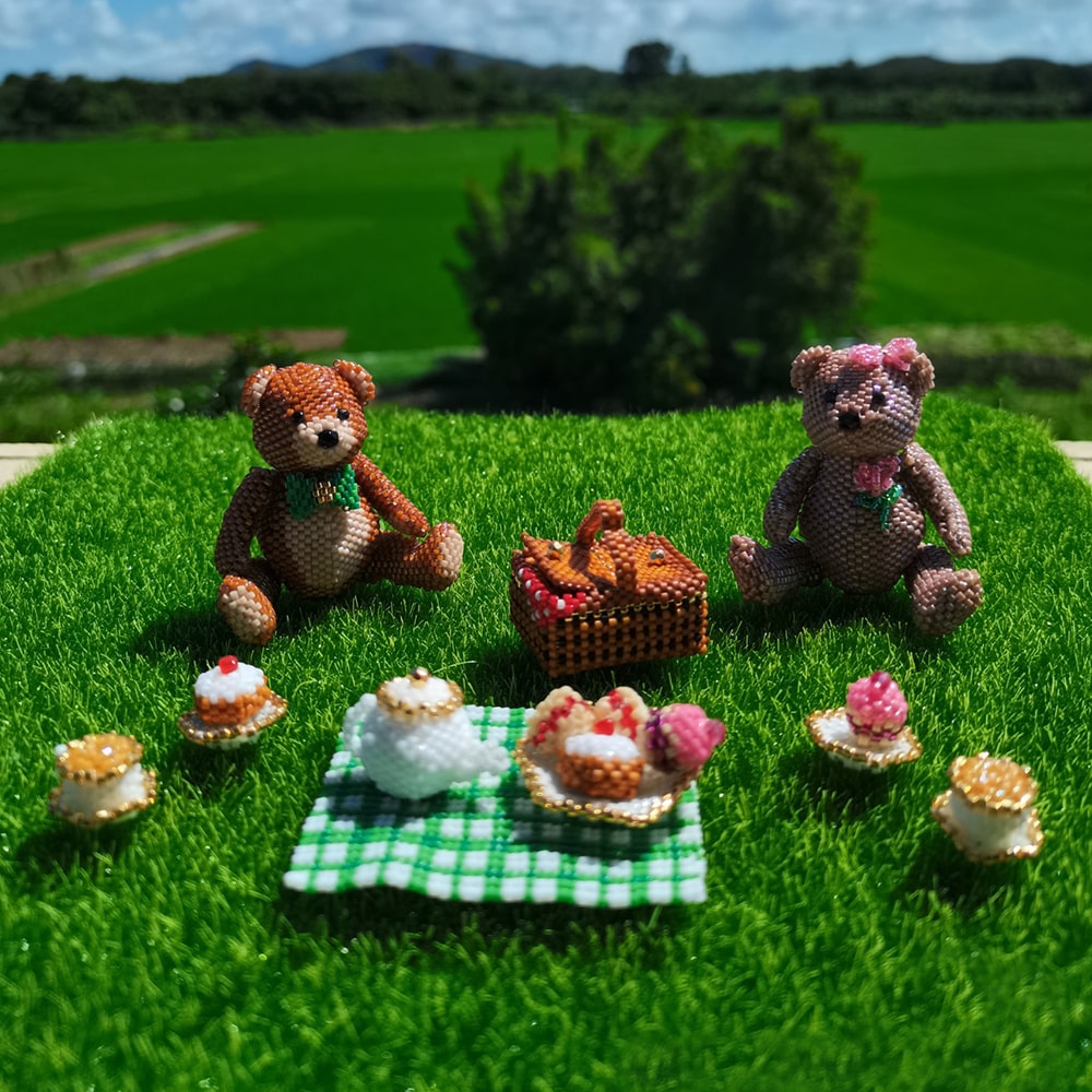 Two teddy bears with a picnic setup on a grassy field