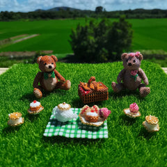 Two teddy bears with a picnic setup on a grassy field