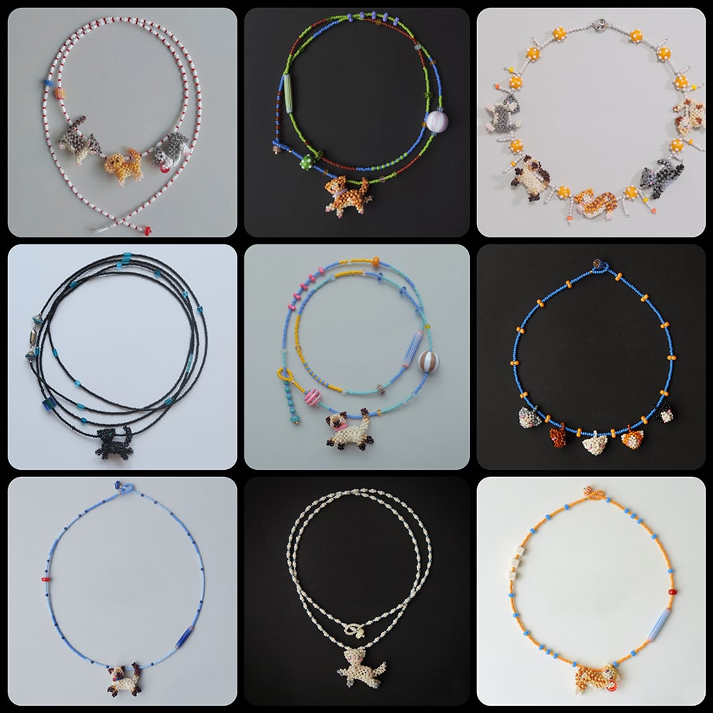Collection of various beaded necklaces with cat charms on a black background