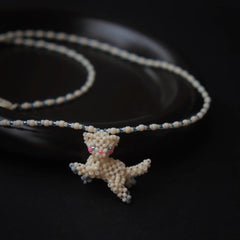 Necklace with a white cat pendant on a dark background