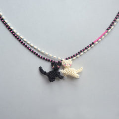 Necklace with black and white cat pendants on a gray background