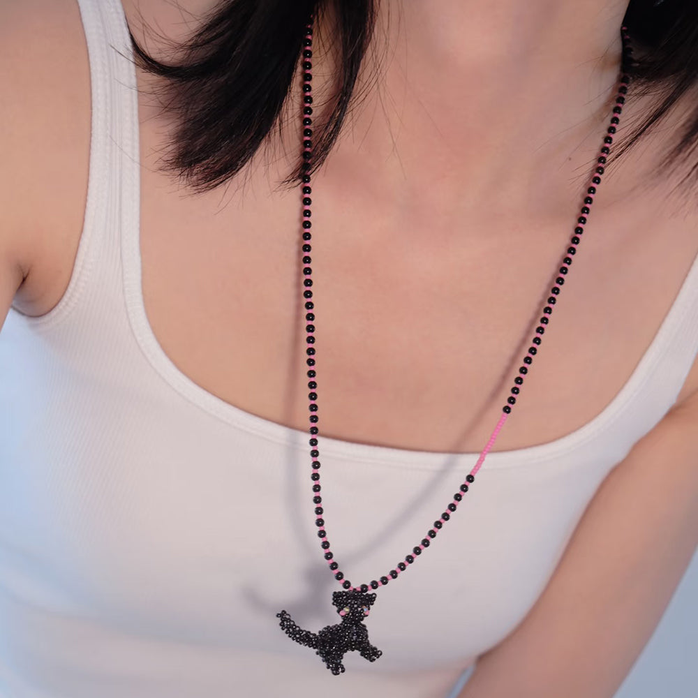 Necklace with a black cat pendant worn by a person in a white tank top.