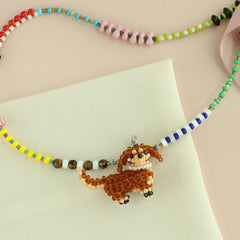 Beaded necklace with a Dachshund dog  pendant on a light pink background