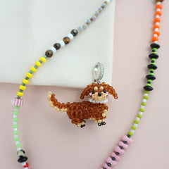 Necklace with a beaded dog pendant on a light pink background