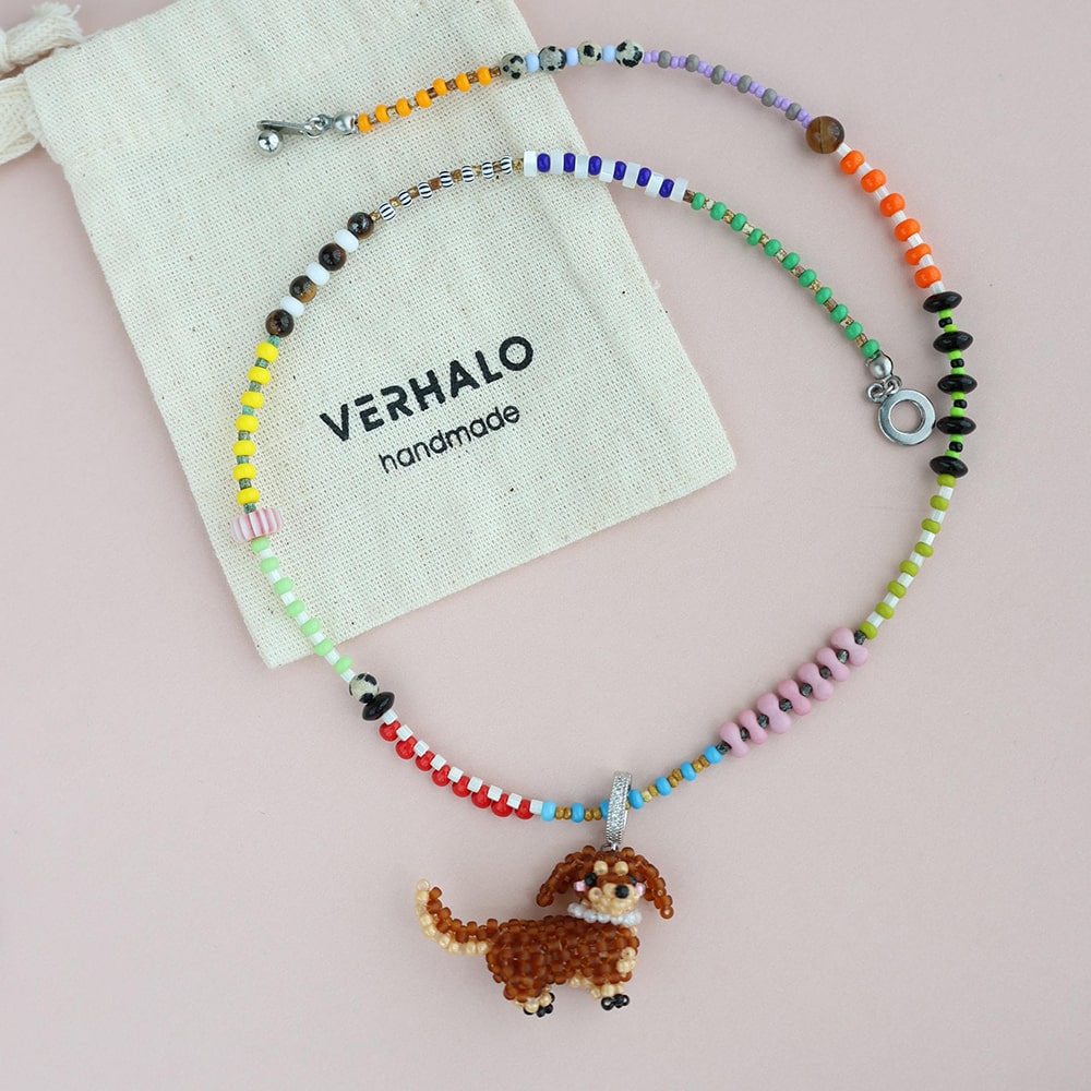 Colorful beaded necklace with a dog pendant on a pink background, featuring the brand 'VERHALO'.