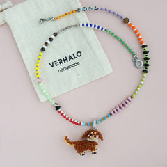 Colorful beaded necklace with a dog pendant on a pink background, featuring the brand 'VERHALO'.