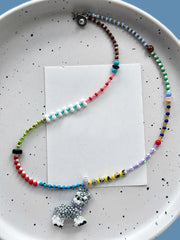 Colorful beaded necklace with a small dog charm on a speckled plate.