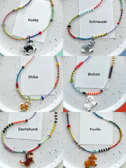 Set of beaded necklaces with dog breed charms on a speckled surface