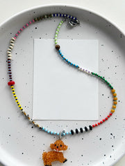 Colorful beaded dog necklace with a dog charm on a speckled plate