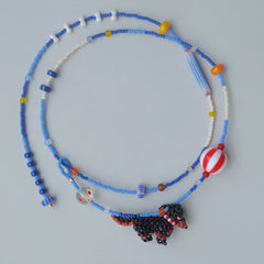 Beaded necklace with a black Dachshund dog pendant on a gray background