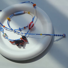 Beaded necklace with a Dachshund dog charm on a white plate
