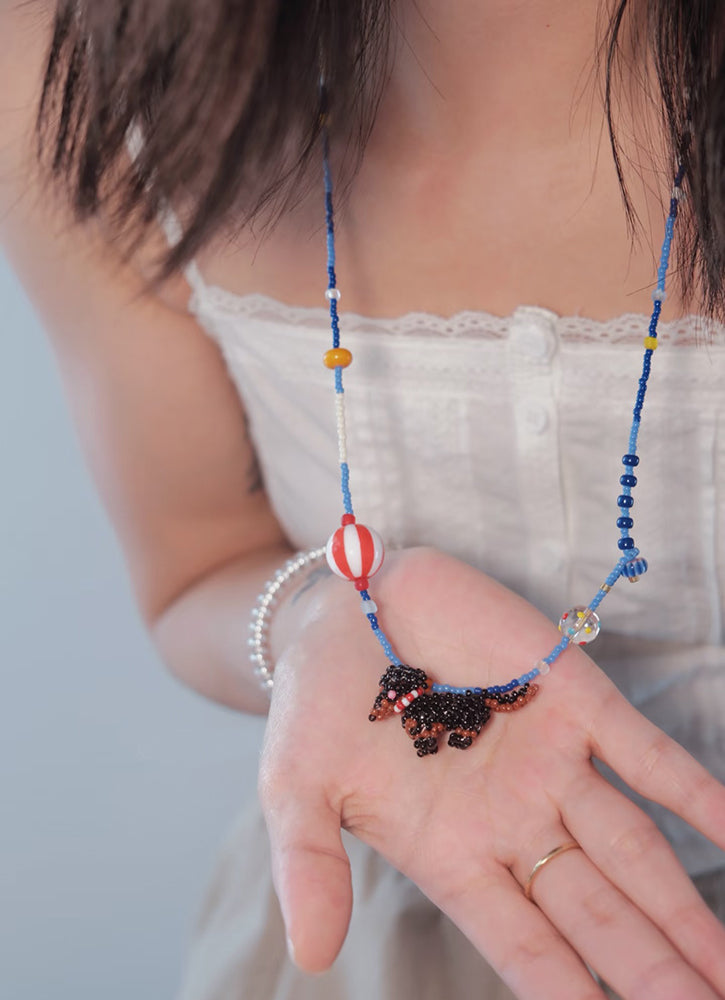 Person wearing a blue beaded necklace with a white top against a light background