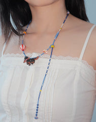 Necklace with colorful beads and a Dachshund dog pendant on a white lace top.