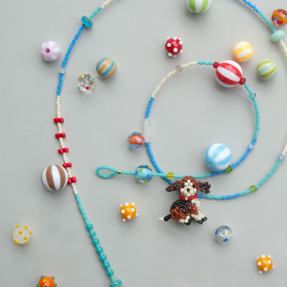 Colorful beaded necklaces with a beagle dog charm on a gray background
