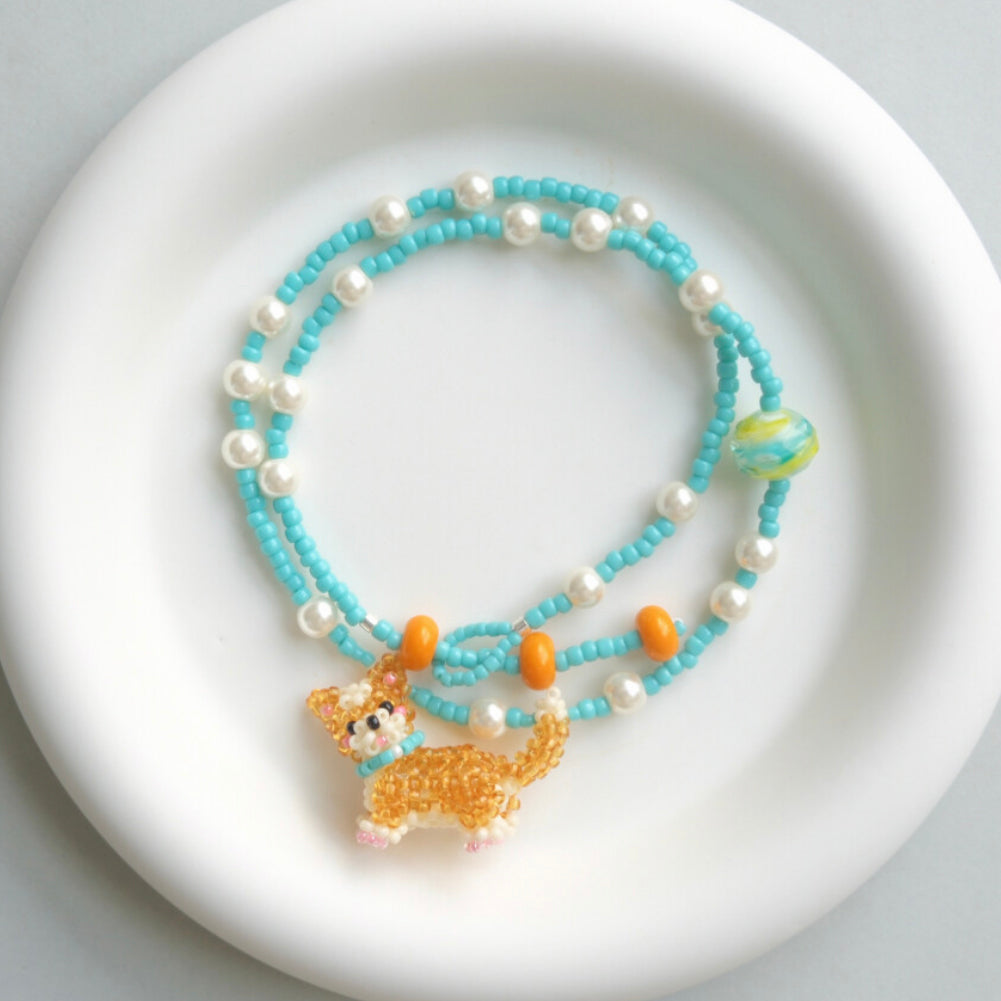 Beaded necklace with a Corgi Dog charm on a white plate