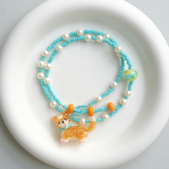 Beaded necklace with a Corgi Dog charm on a white plate