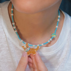 Necklace with a Corgi Dog pendant held by a person wearing a white shirt.