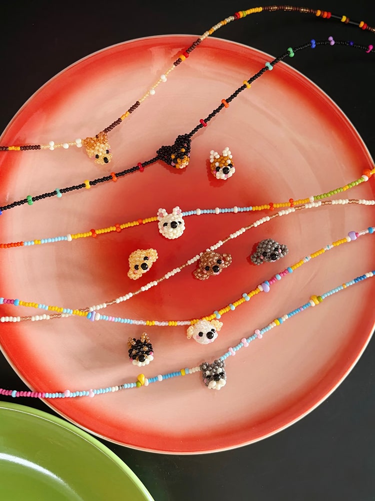 Colorful beaded necklaces on a red plate with a black background