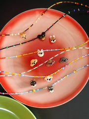Colorful beaded necklaces on a red plate with a black background
